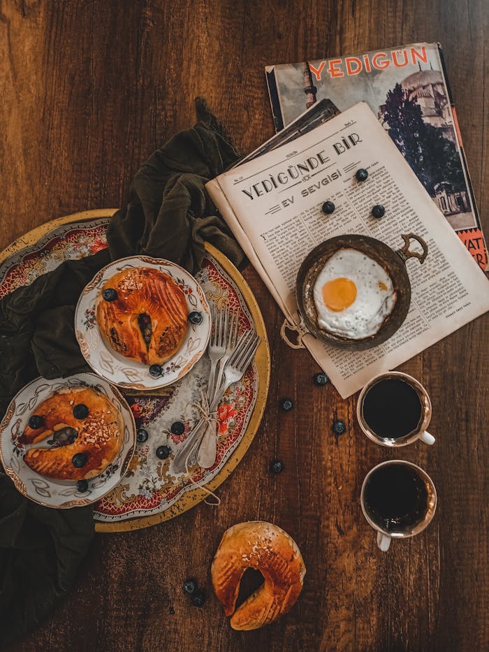 Delicious Turkish breakfast spread with pastries, coffee, and newspaper on a wooden table.